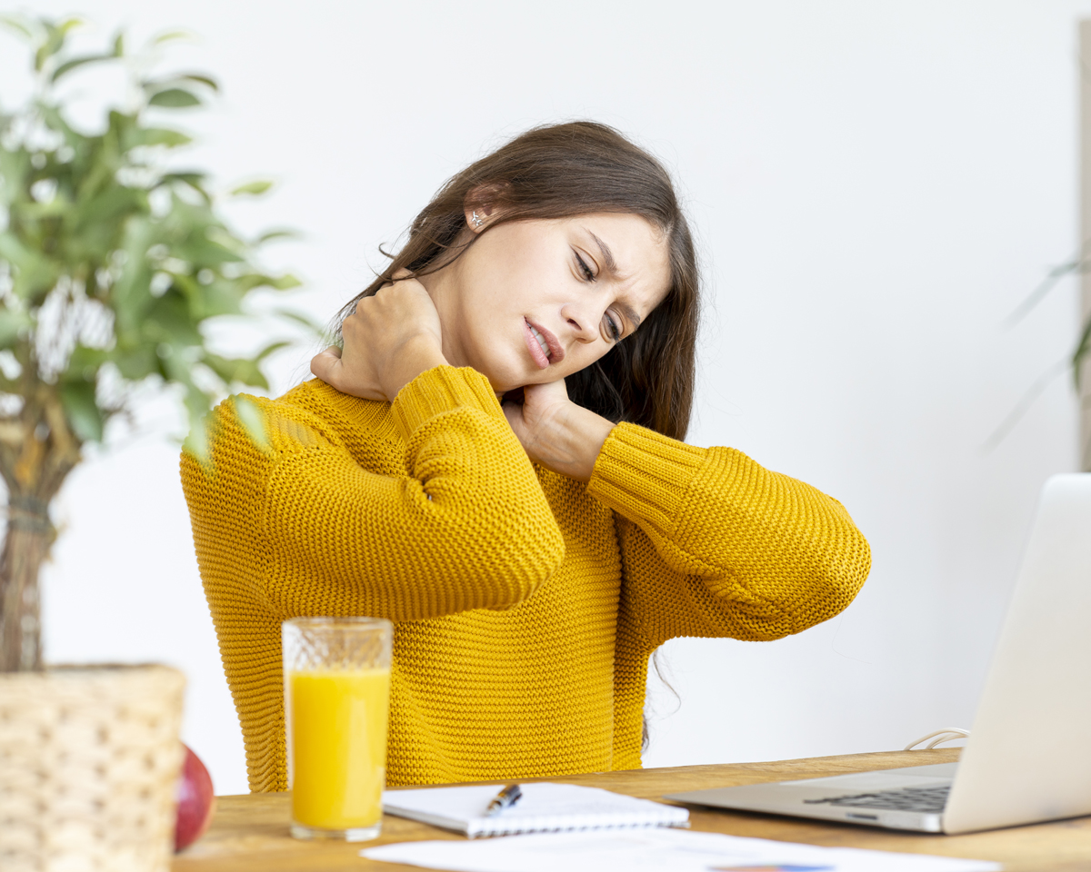 Woman massaging neck pain from working at computer