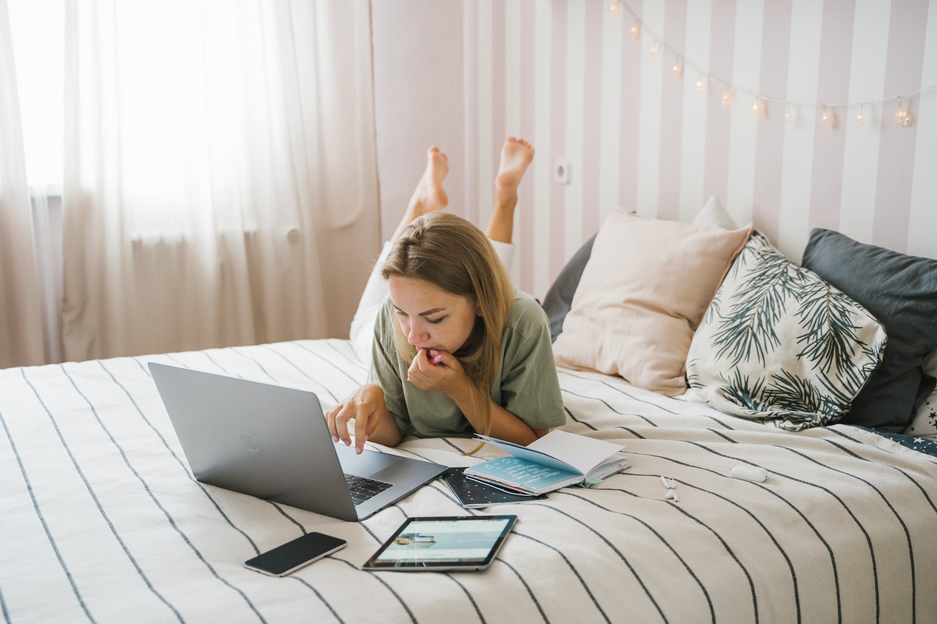 woman in green shirt using macbook air on bed