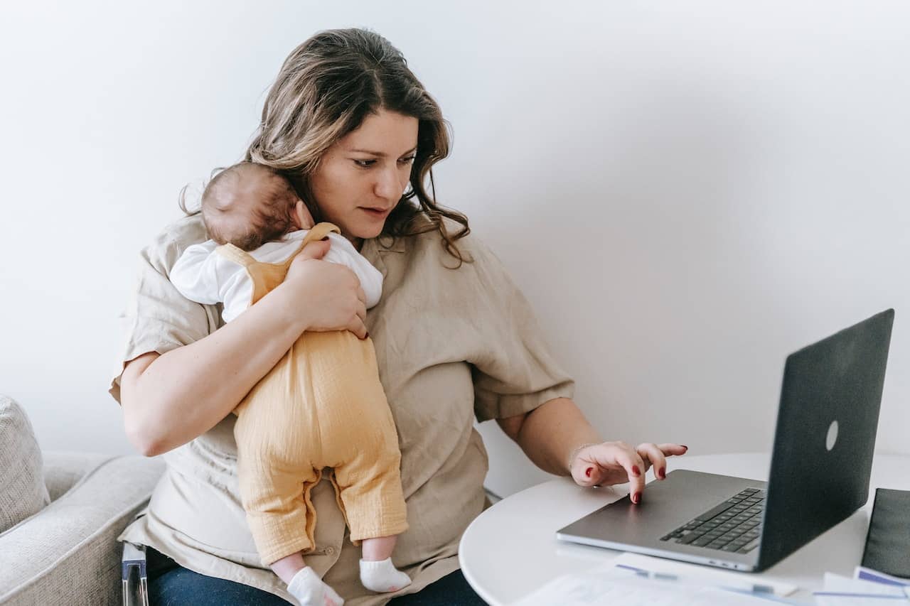 women working on computer holding baby